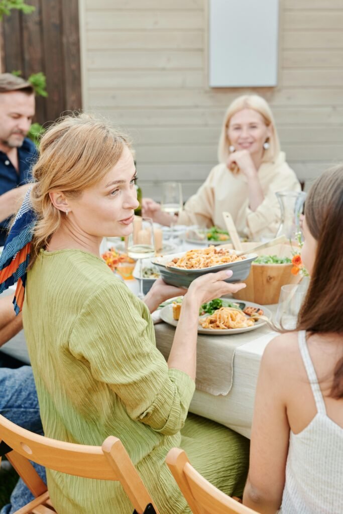Family enjoying a meal together outdoors in a relaxed setting, perfect for summer.