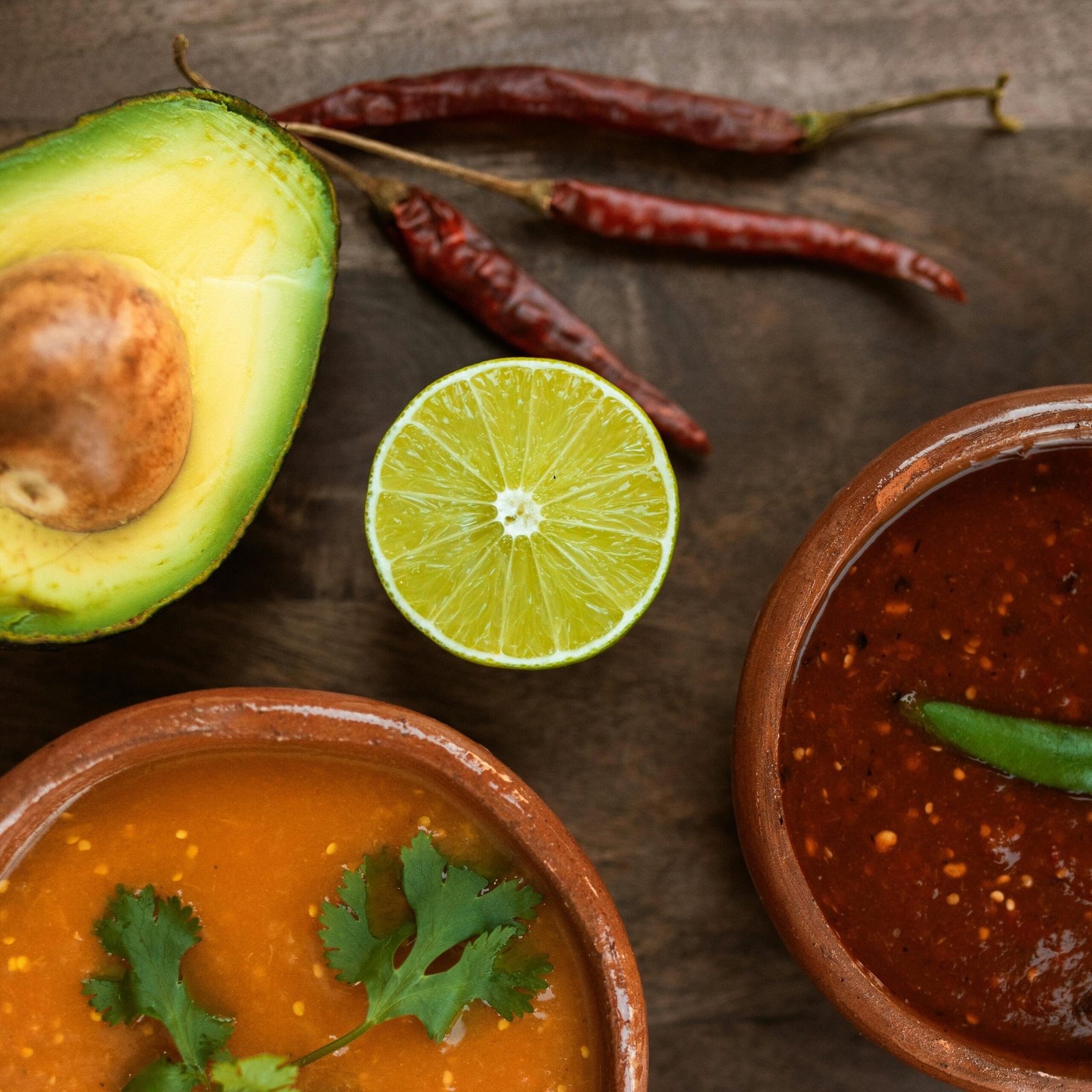 Top view of Mexican salsas with avocado and lime slices, vibrant and delicious.